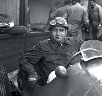 Juan Manuel Fangio con casco y antiparras en su auto de carrera